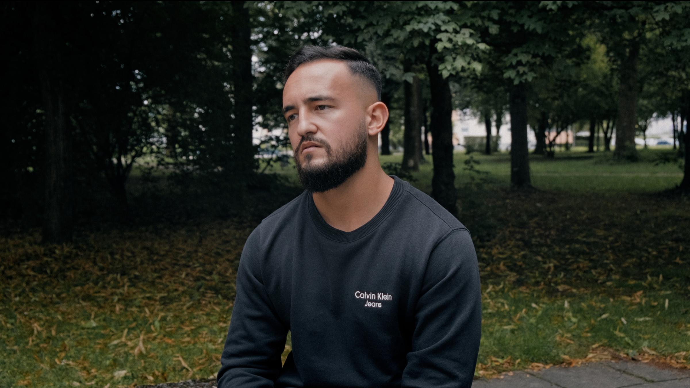 "Einzeltäter - München": Arbnor Sequashi sitzt trauernd mit hängenden Schultern in einem Park. Er blickt gedankenverloren ins Leere.