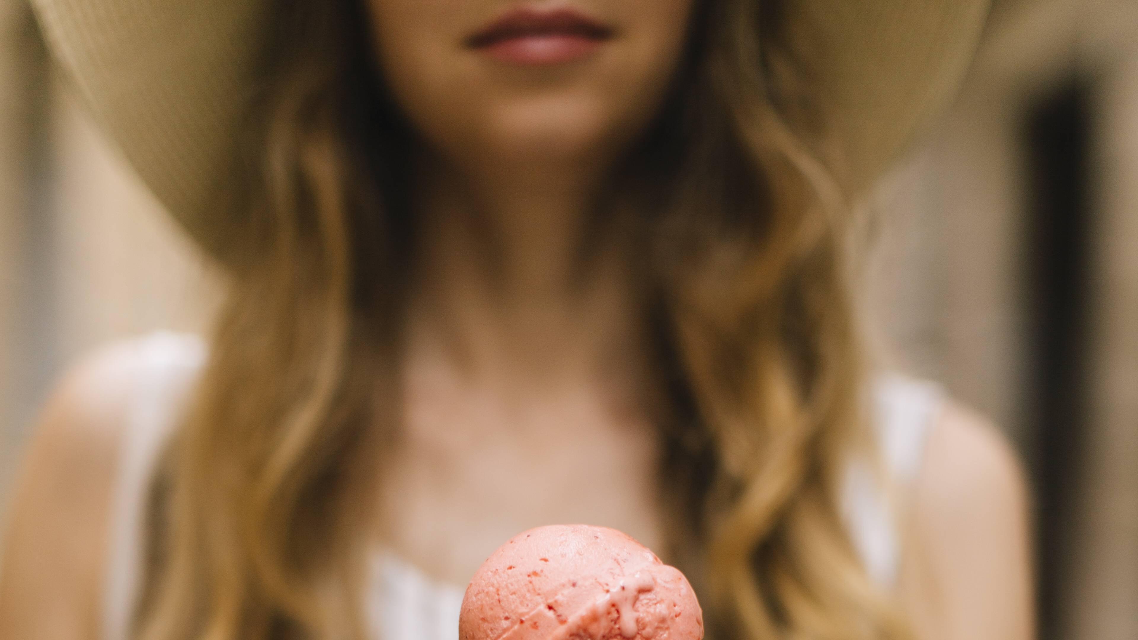 Ein Mädchen hält ein buntes Eis in einer Waffel in der Hand