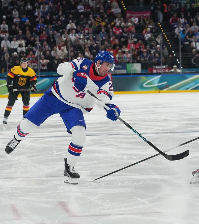 Der US-amerikanische Eishockeyspieler Brock Nelson spielt den Puck durch die Beine des deutschen Eishockeyspielers Moritz Seider durch 