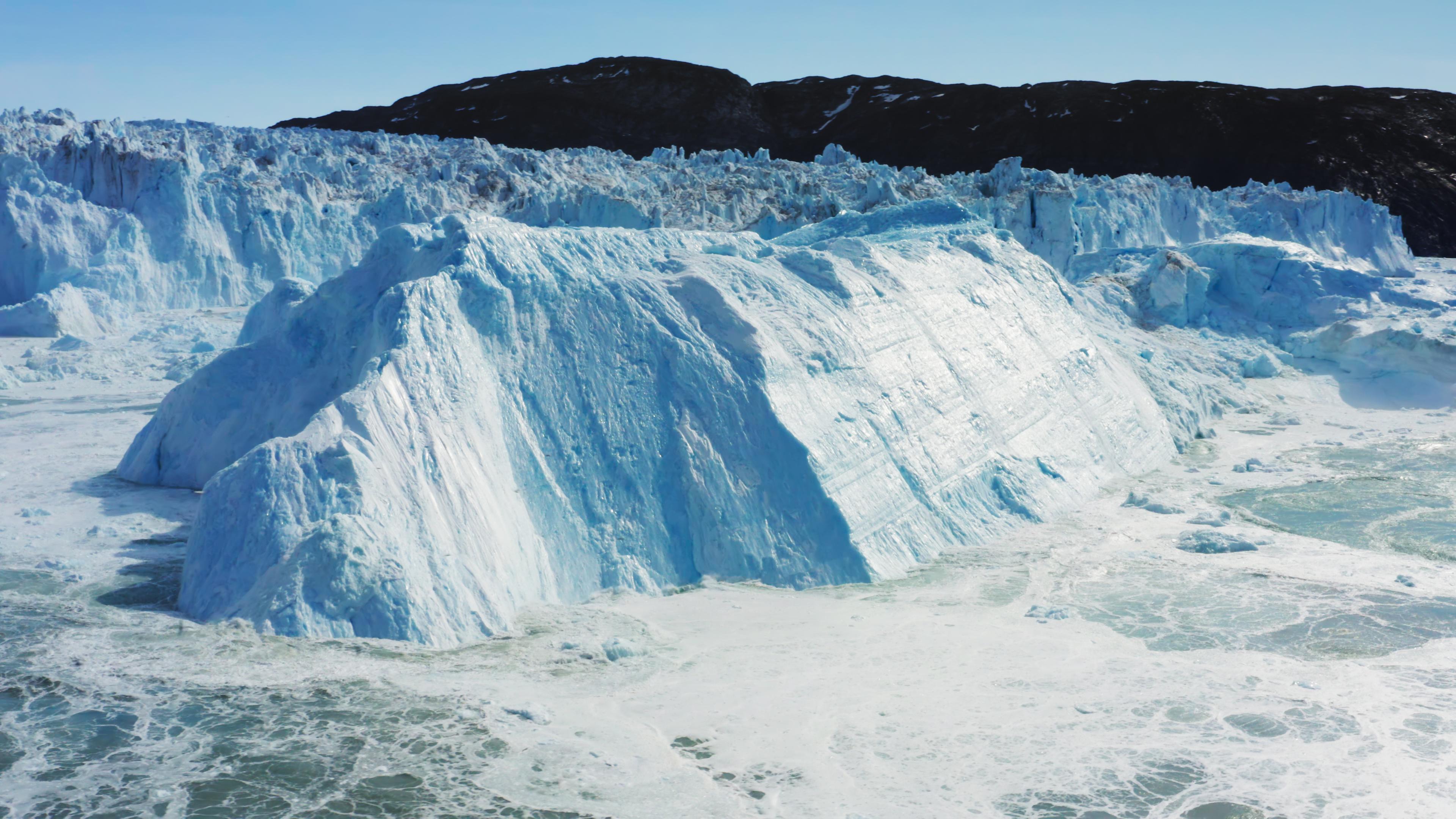 Ein großes Stück Eis bricht von einem Gletscher ins Meer.