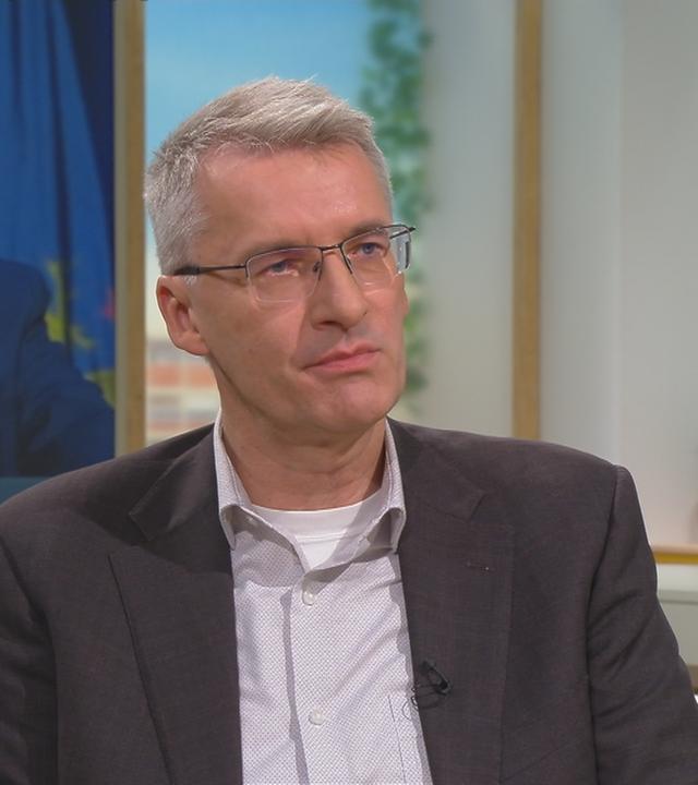 ZDF-Journalist Elmar Theveßen im Volle-Kanne-Studio. Im Hintegrund ein Foto von Donald Trump.