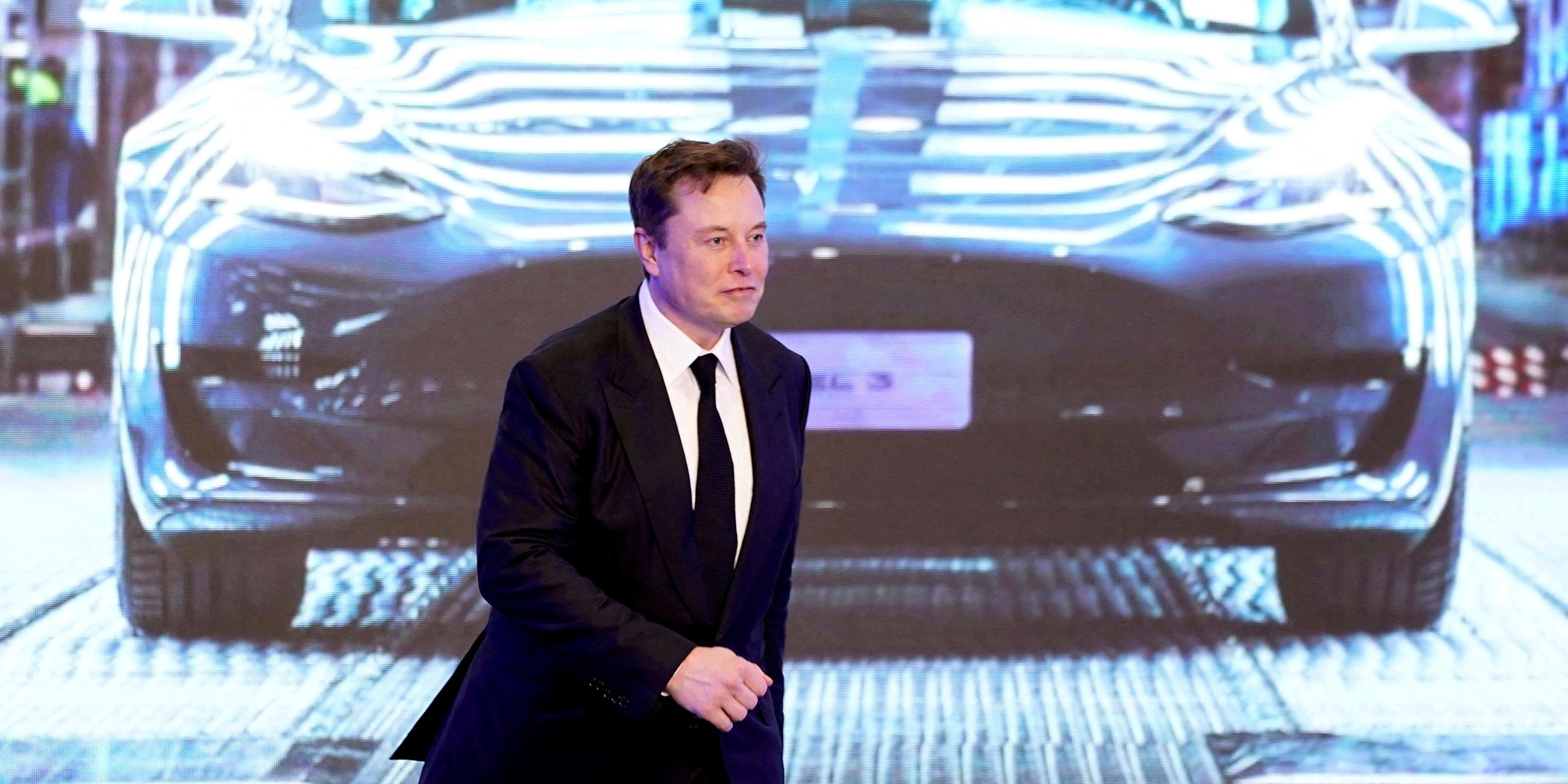 Elon Musk vor einem Bild des Tesla Model 3 
