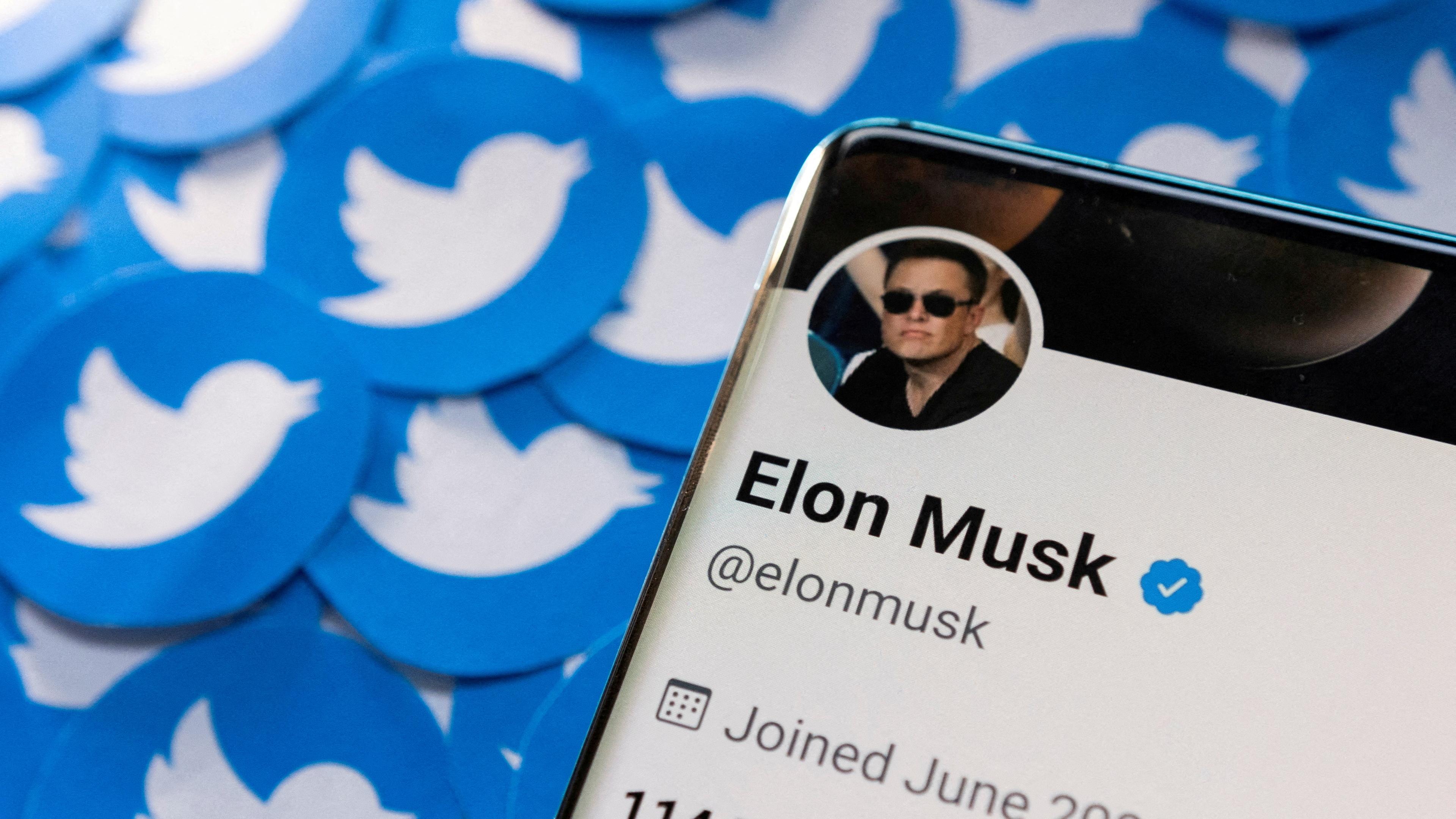 Ein Smartphone mit dem Twitter-Profil von Elon Musk liegt auf gedruckten Twitter-Logos