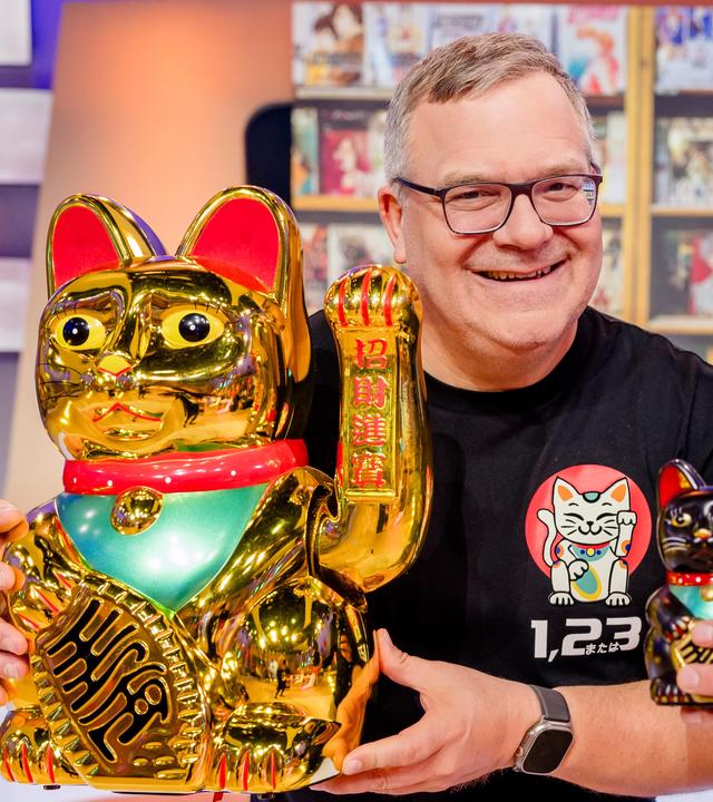 Manga-Experte Nino Kerl (r.) und Elton halten Winkekatzen in unterschiedlicher Größer.