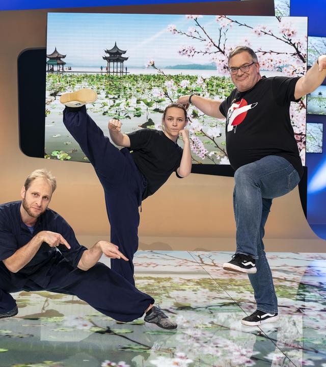 Kung-Fu-Meister Arno Wünsch, Kung-Fu-Trainerin Marina Berljafa und Elton stehen im Studio und präsentieren Posen aus verschiedenen Kung-Fu-Stilen.