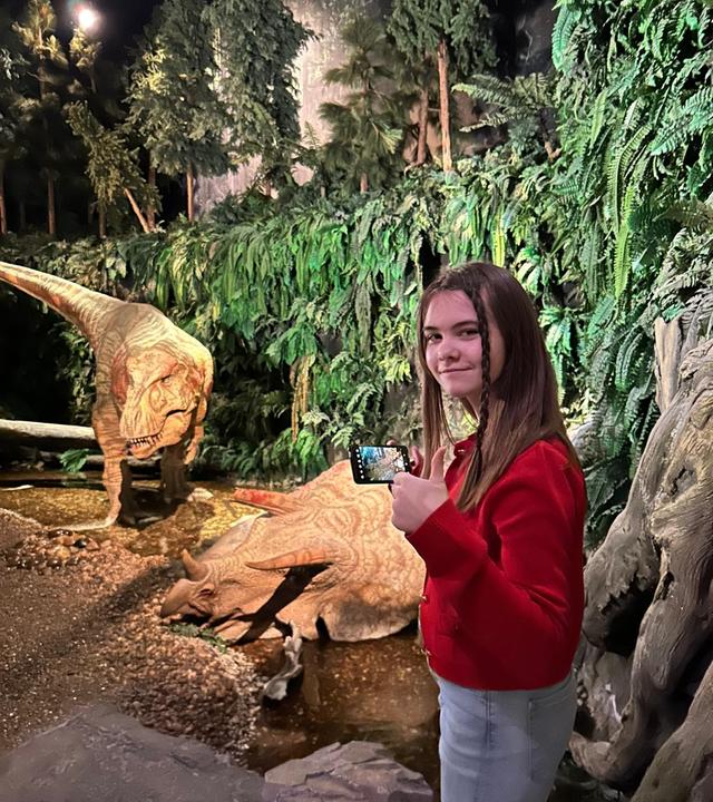 Mädchen steht vor einem Dino