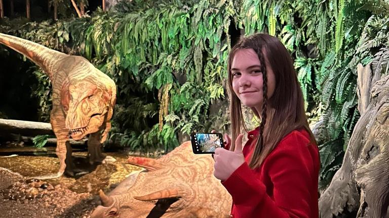 Mädchen steht vor einem Dino
