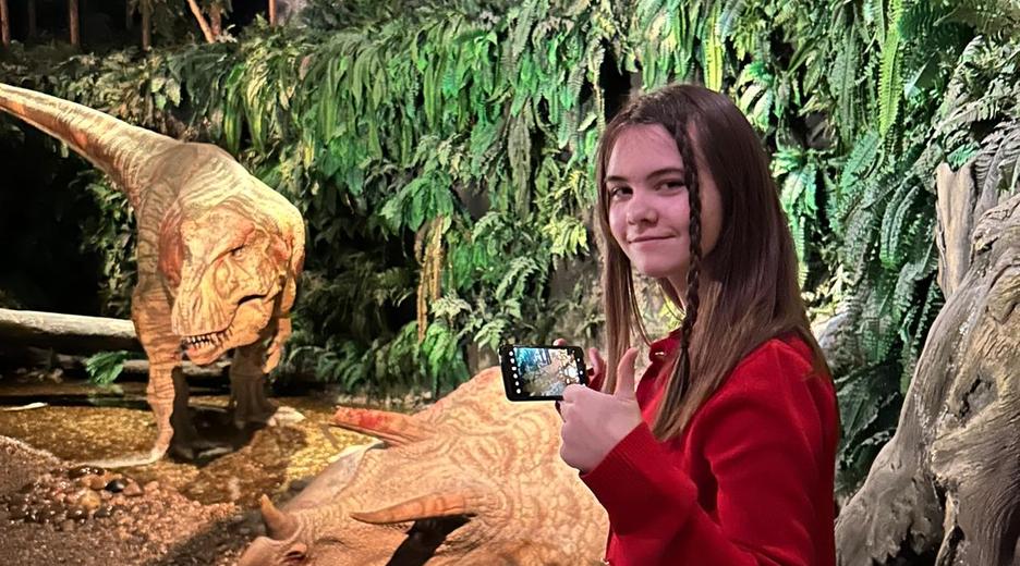 Mädchen steht vor einem Dino