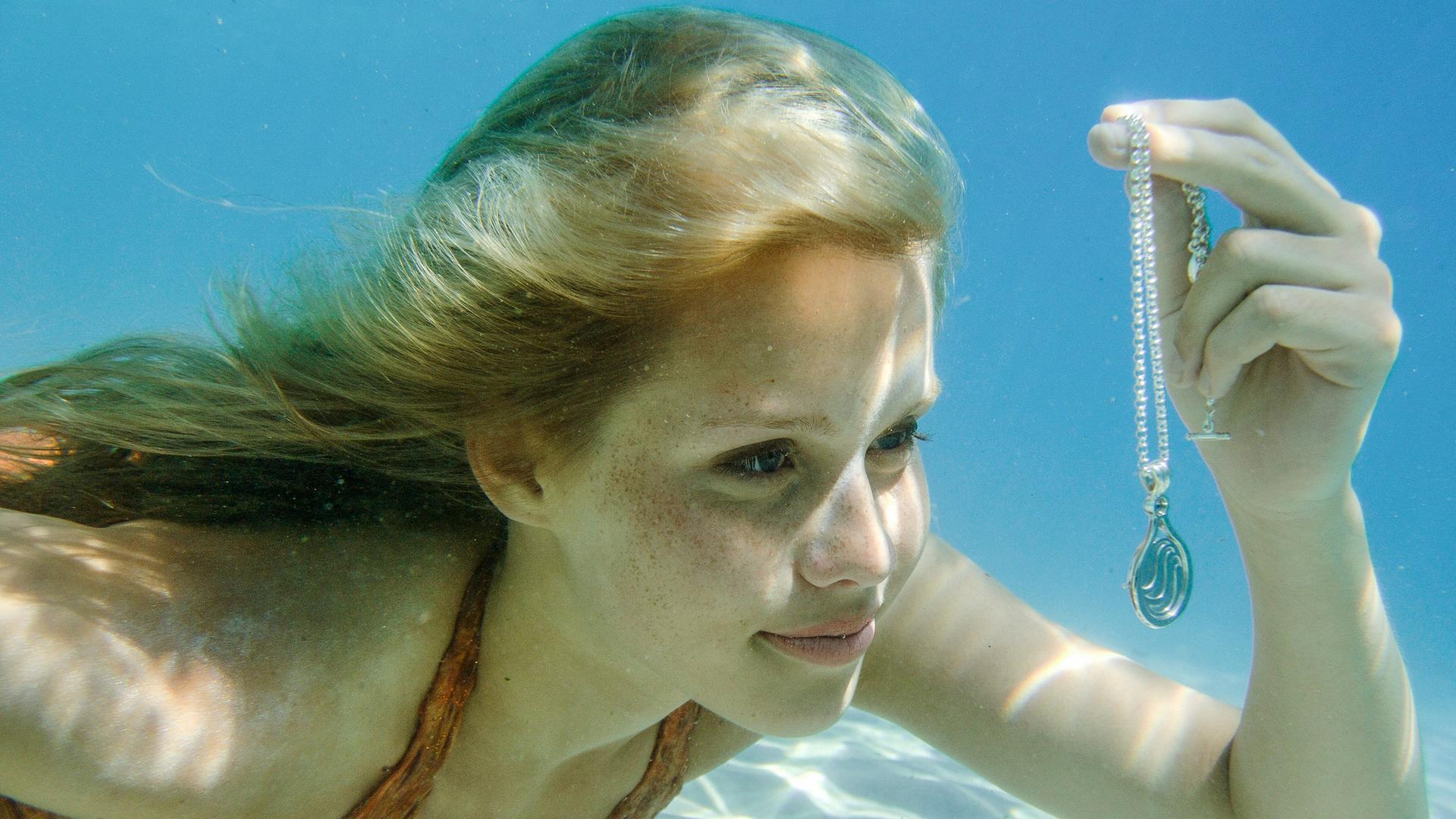 Meerjungfrau Emma findet im Meer eine Kette mit Anhänger.