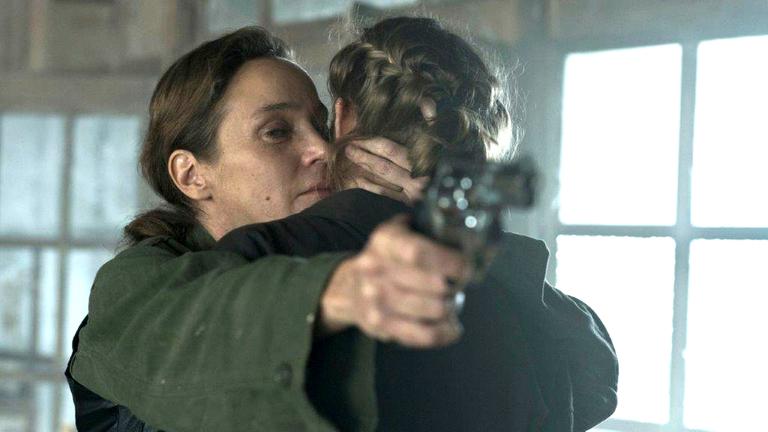 "Westwall - Kapitel VI": Ira (Jeanette Hain) hält Julia (Emma Bading) im Arm und zielt gleichzeitig mit einer Pistole auf die andere Seite des Raums.