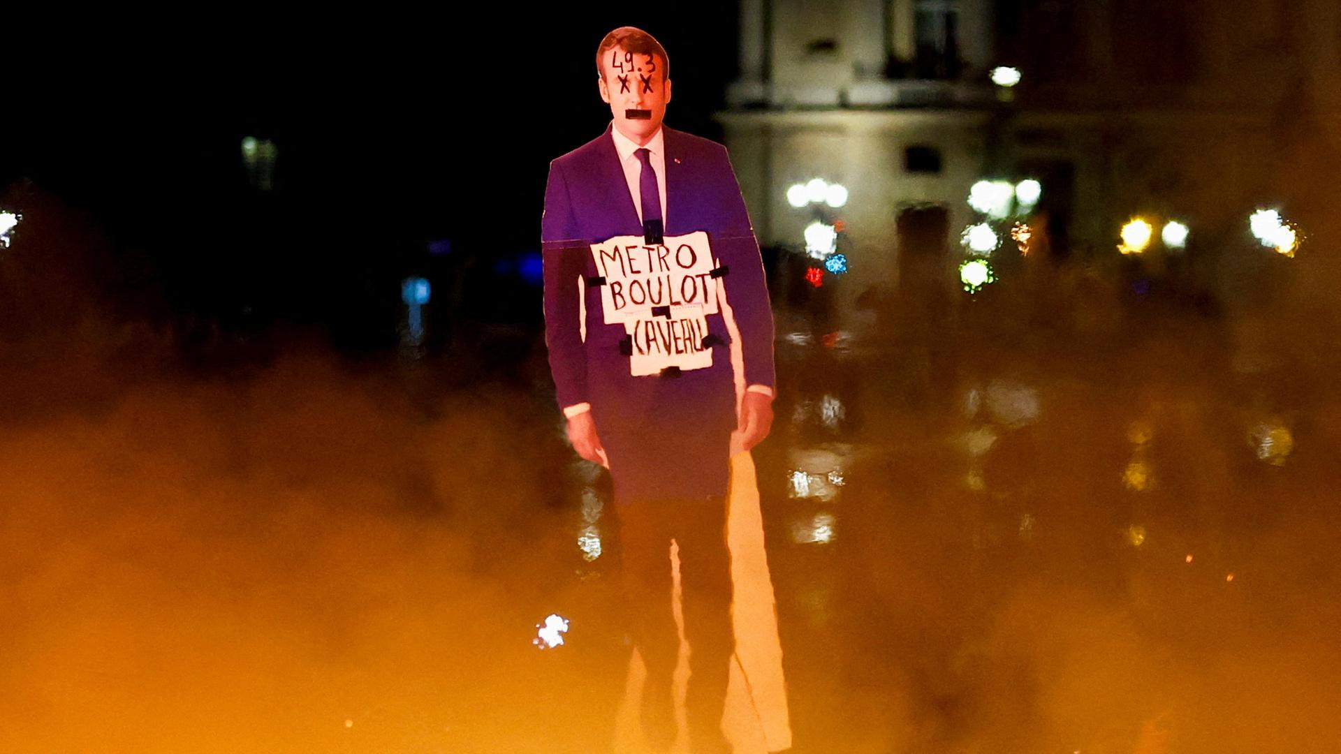 Pappfigur von Emmanuel Macron. Im Vordergrund Feuer