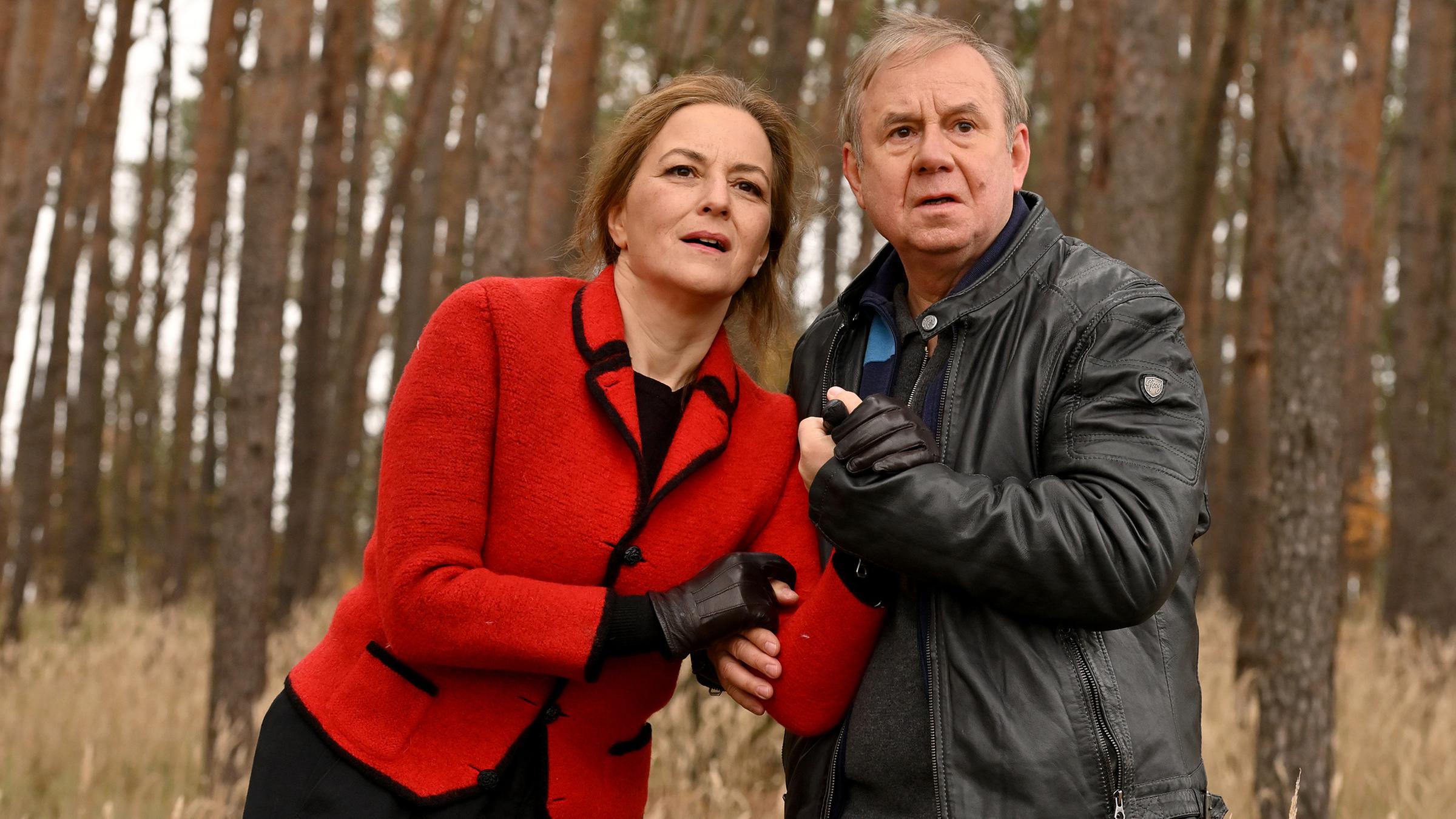 Georg Weiser (Joachim Król) und Petra Schultheiss (Martina Gedeck) stehen an einem herbstlichen Waldrand. Er stützt sie, beide schauen interessiert in die Ferne.