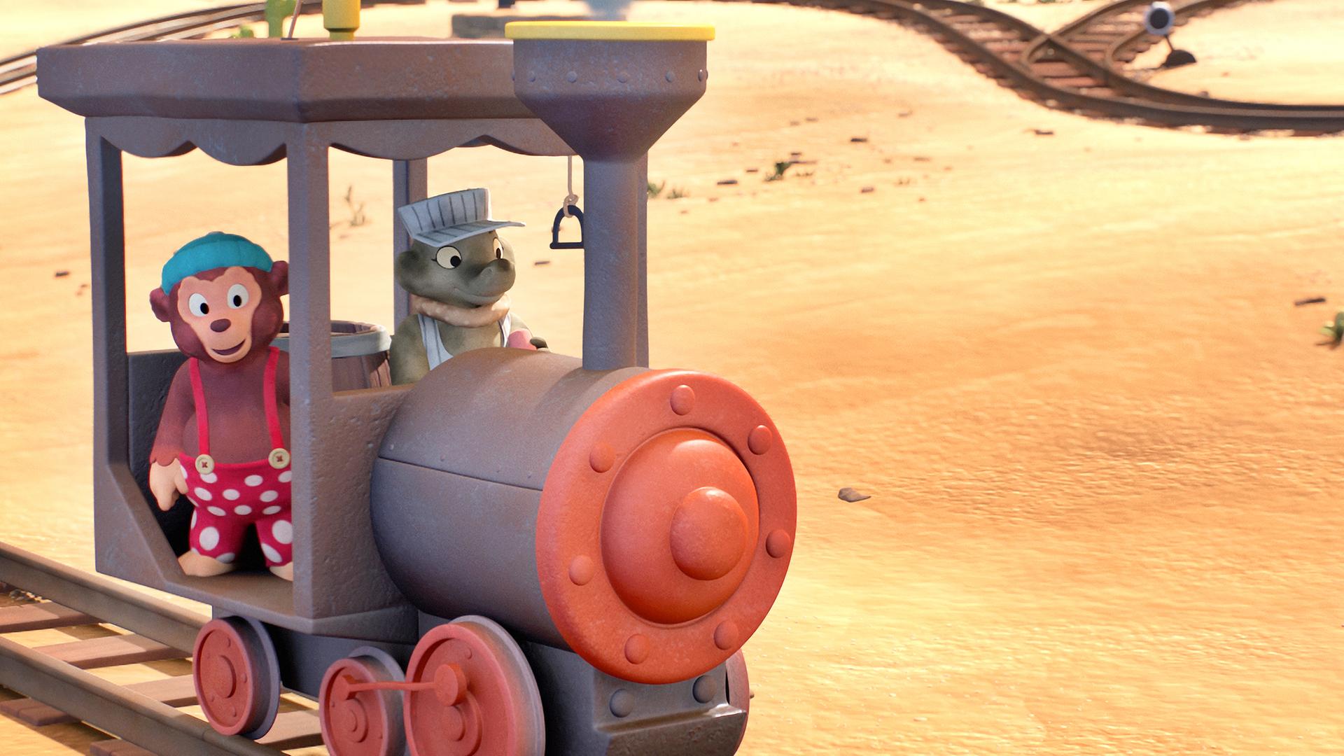 Petzi (links) sitzt gemeinsam mit dem Krokodilmädchen Paffhanna in seiner Lokomotive in der Wüste. Sie trägt eine Sonnenbrille und eine Mütze. Aus der Lokomotive steigt Dampf auf, im Hintergrund liegen Steine und vereinzelnd wachsen Kaktuspflanzen.