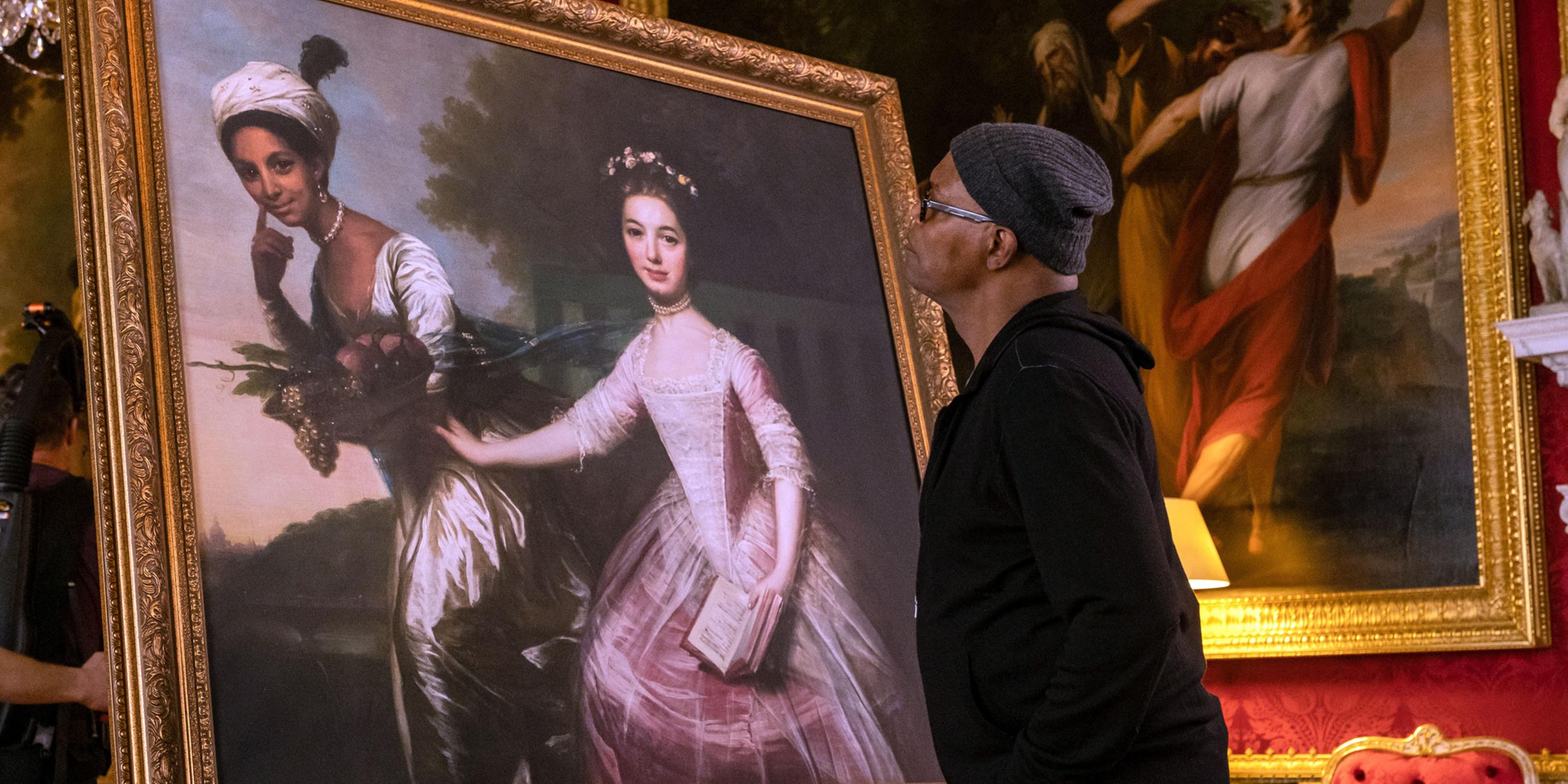Samuel L. Jackson schaut auf ein historisches Gemälde mit zwei Frauen in prächtigen Kleidern.