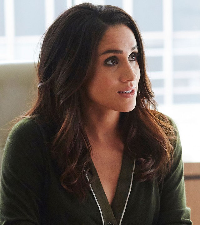"Suits - Entgleist": Rachel (Meghan Markle) sitzt im Büro an einem Schreibtisch. Ihre Hände sind ineinandergelegt, halten einen Stift und liegen auf der Tischplatte auf einem Block.