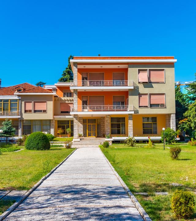 Bild eines zweistöckigen Gebäudes mit einstöckigem Nebenbau.