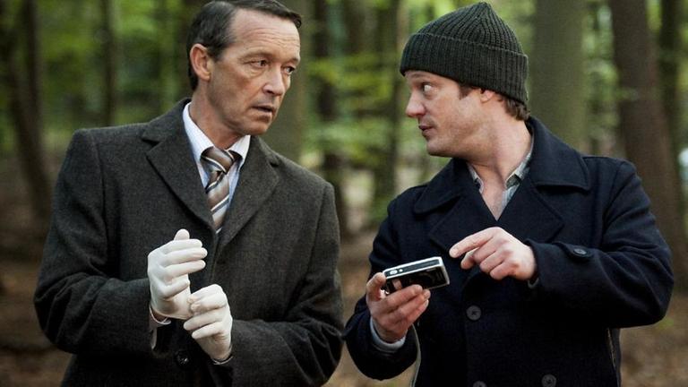 Hauptkommissar Torsten Wallat (Michael Roll, l.) schaut auf die Ermittlungsmethoden seines Kollegen Janssen (Aurel Manthei, r.) ziemlich herablassend.