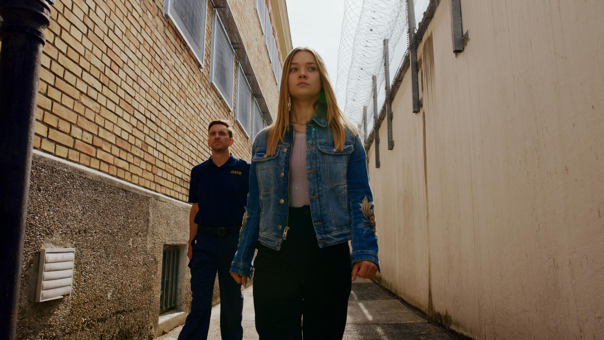 "Gestern waren wir noch Kinder (5)": Vivi Klettmann (Julia Beautx) ist auf dem Weg ins Gefängnis. Ihr Blick ist traurig, aber dennoch gefasst. Sie wird von einem Gefängniswärter begleitet.