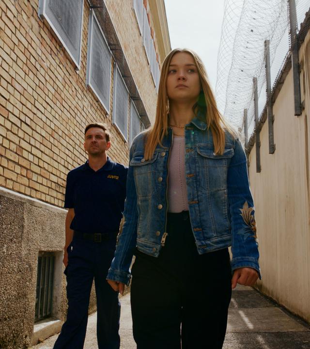 "Gestern waren wir noch Kinder (5)": Vivi Klettmann (Julia Beautx) ist auf dem Weg ins Gefängnis. Ihr Blick ist traurig, aber dennoch gefasst. Sie wird von einem Gefängniswärter begleitet.