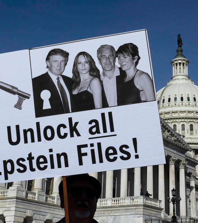 Ein Mann hält ein Plakat hoch, auf dem ein Foto von Trump, Epstein und zwei Frauen zu sehen ist, mit der Forderung, alle Akten offen zu legen.