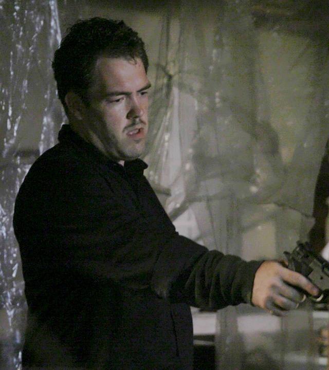 "Erbarmungslos: Israel Keyes - Das fast perfekte Verbrechen": Filmszene: Ein Mann hält eine Pistole in der Hand und zielt nach unten.