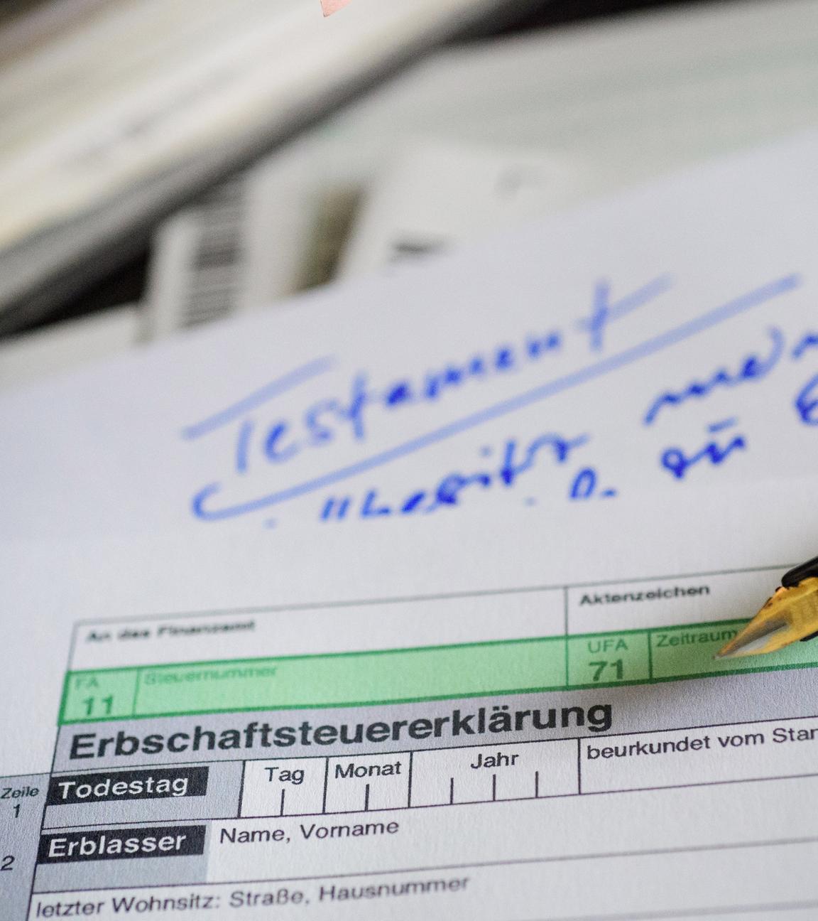 Ein Formular zur Erbschaftssteuer liegt über einem Papier mit der Aufschrift "Testament".