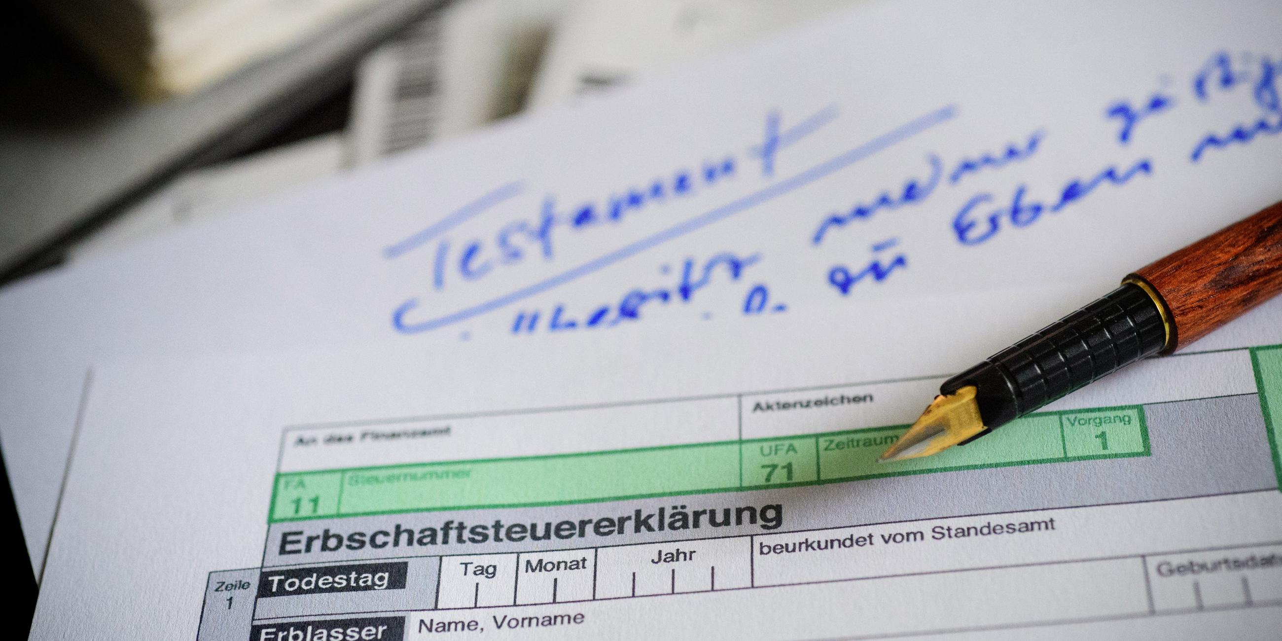 Ein Formular zur Erbschaftssteuer liegt über einem Papier mit der Aufschrift "Testament".