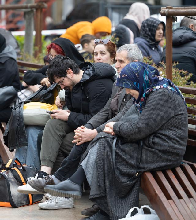 Menschen mit ihren Habseligkeiten sitzen nach einem starken Erdbeben in Istanbul in einem Park.