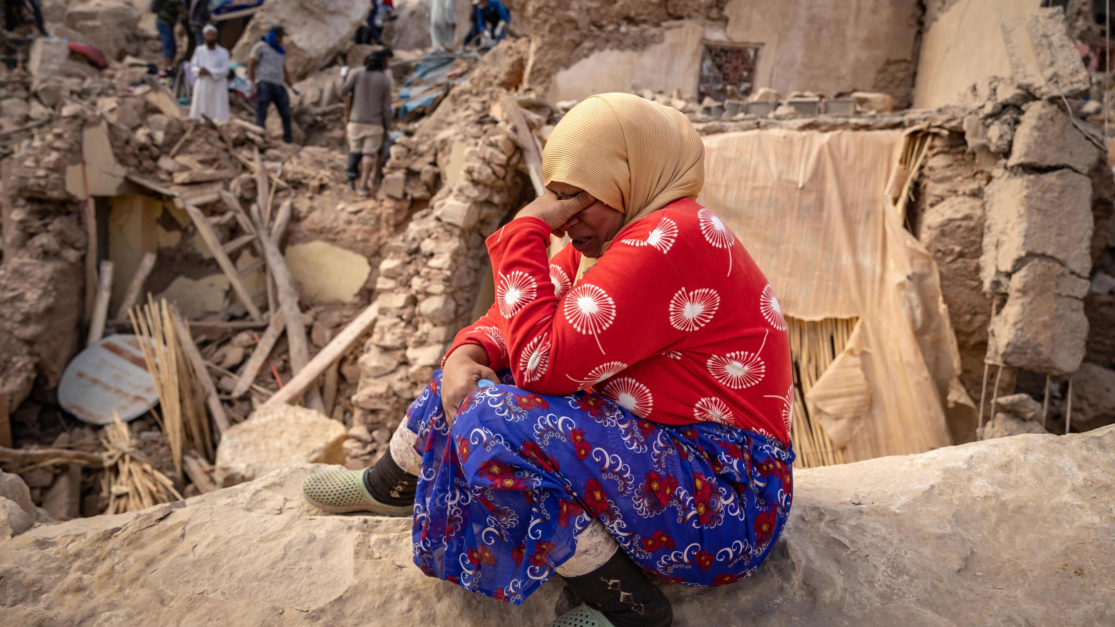 Verzweifelte Frau sitzt in den Trümmern im Erdbebengebiet in Marokko.