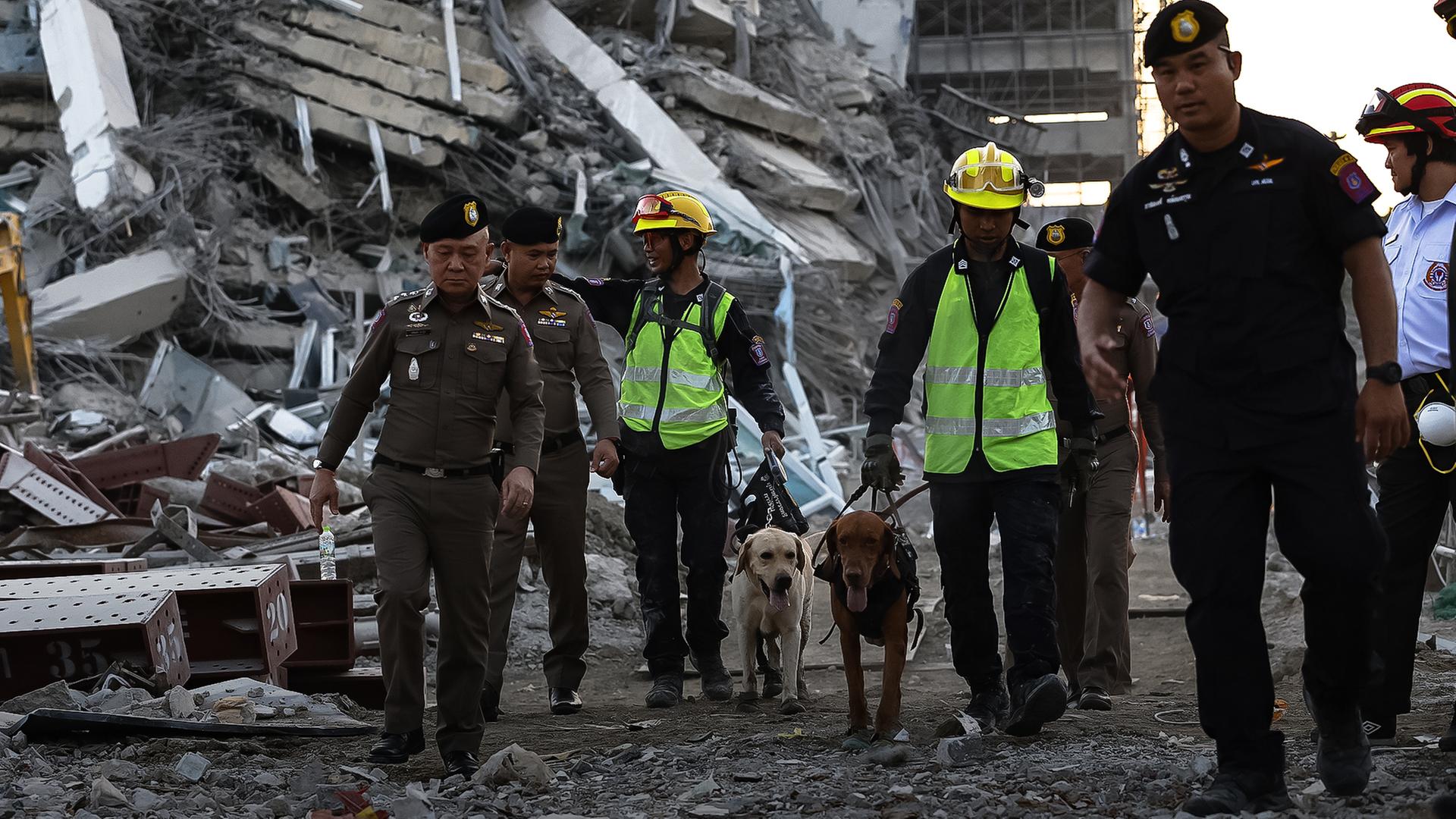 Menschen durchsuchen Trümmer, die durch ein Erdbeben enstanden.