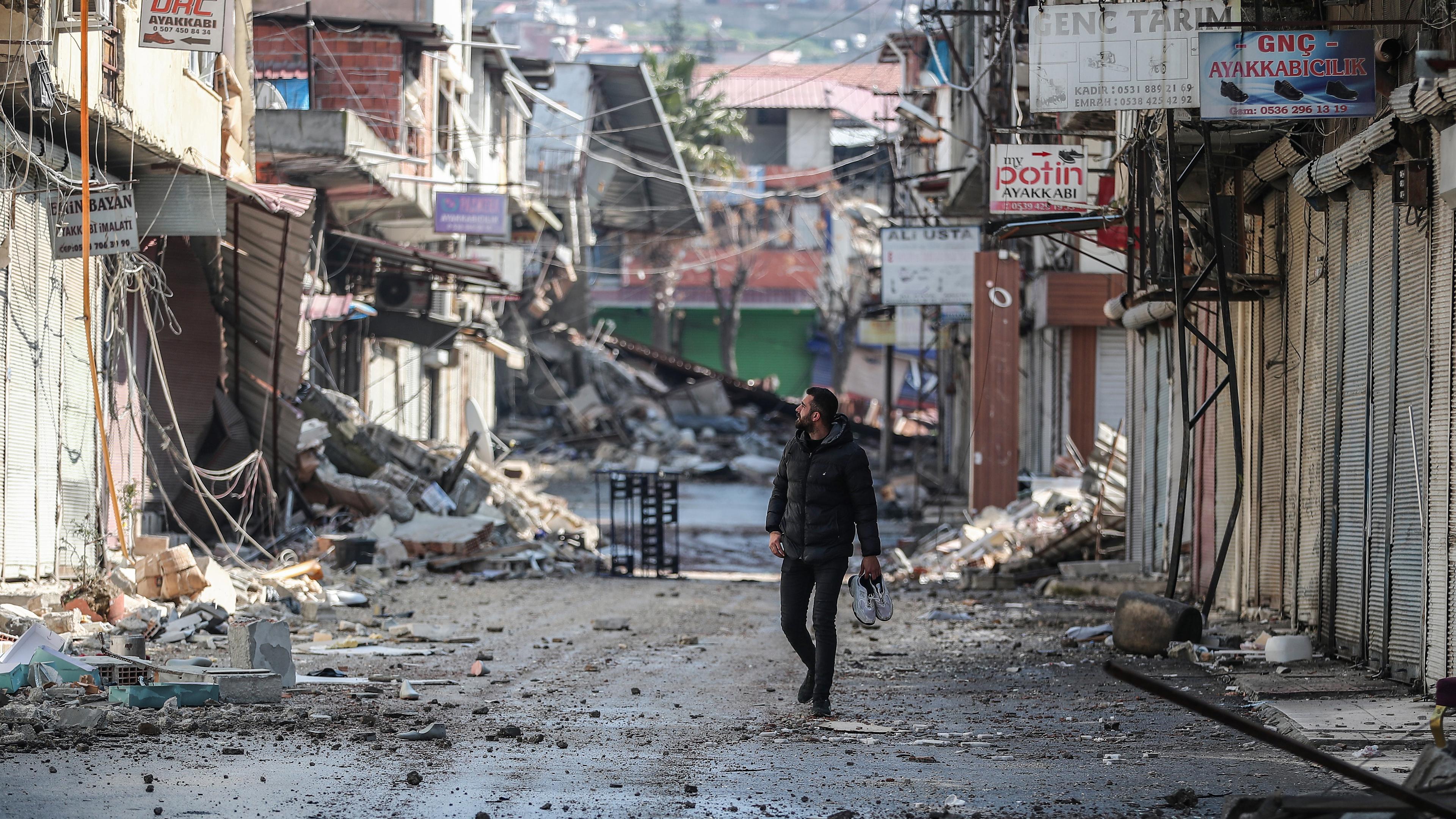 Ein Mann betrachtet sein beschädigtes Geschäft im Industriegebiet nach einem starken Erdbeben in Hatay (Türkei), aufgenommen am 21.02.2023 