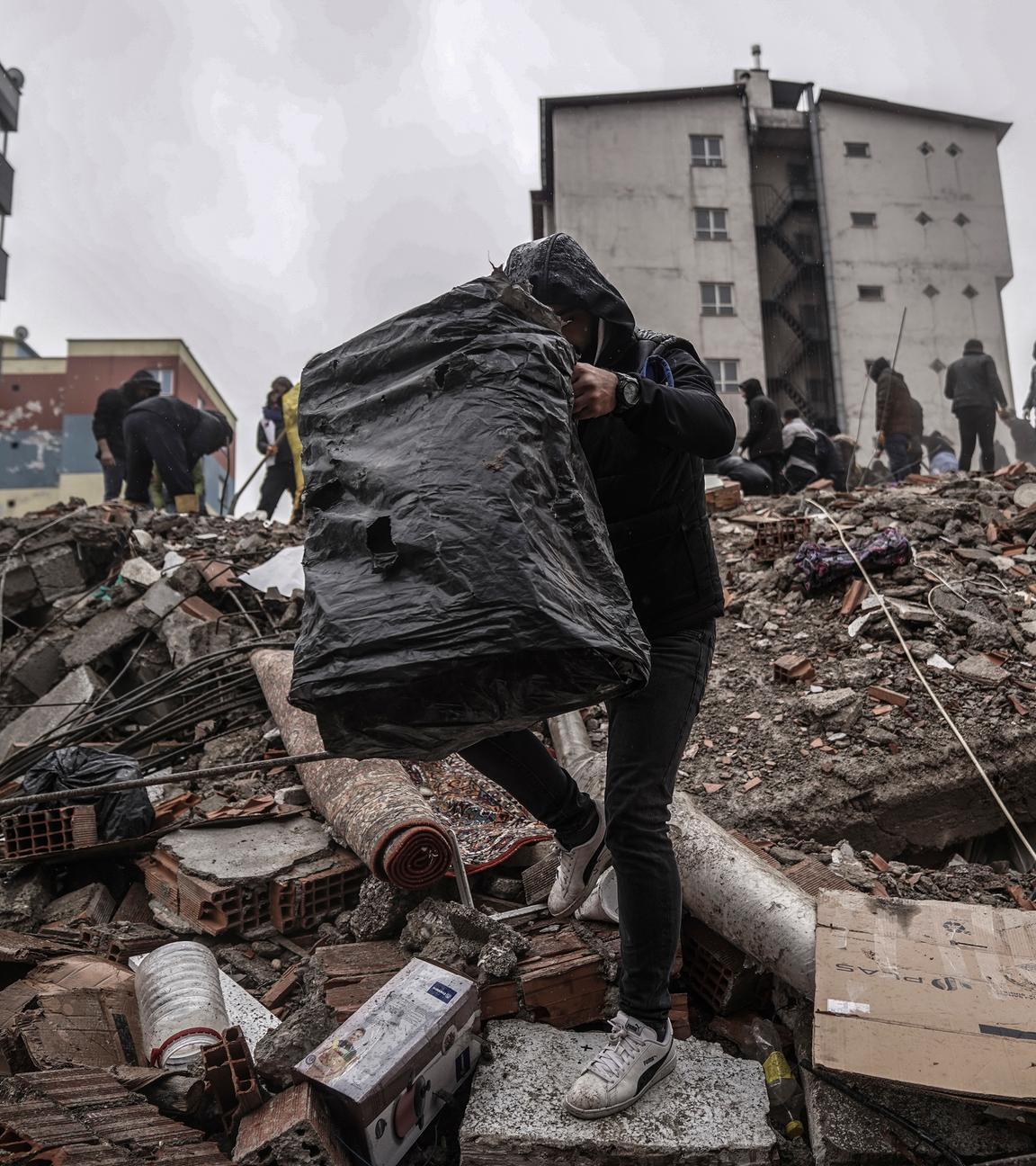Türkei, Gaziantep: Menschen und Rettungskräfte suchen nach Menschen in den Trümmern eines zerstörten Gebäudes.