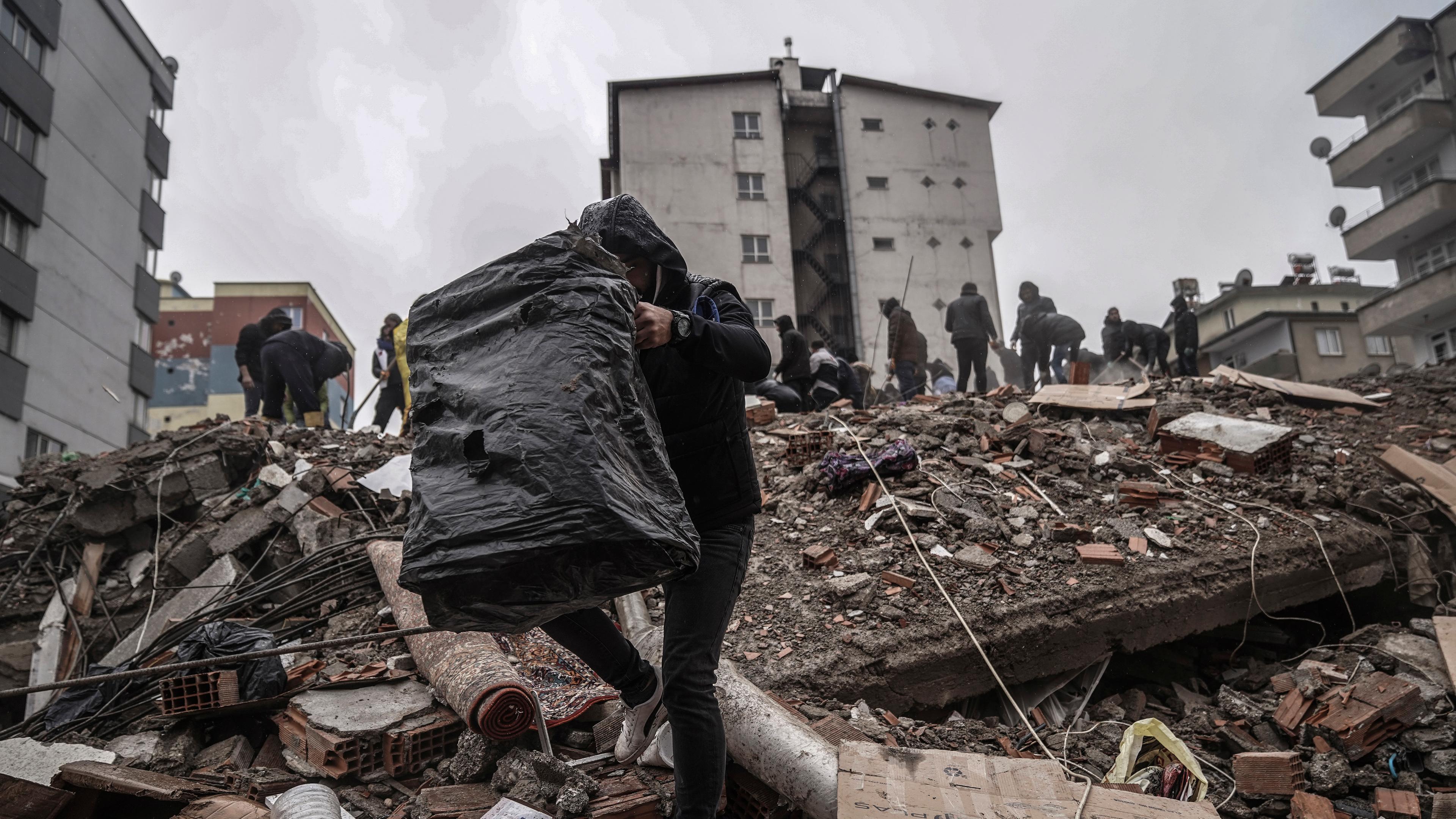 Türkei, Gaziantep: Menschen und Rettungskräfte suchen nach Menschen in den Trümmern eines zerstörten Gebäudes.