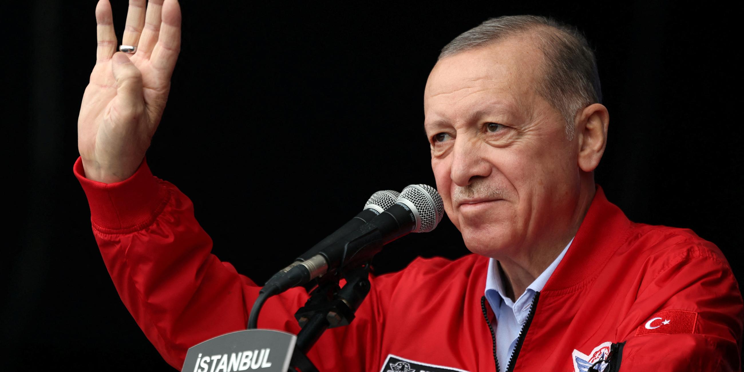 Präsident Recep Tayyip Erdogan mit roter Windjacke am Mikrofon.
