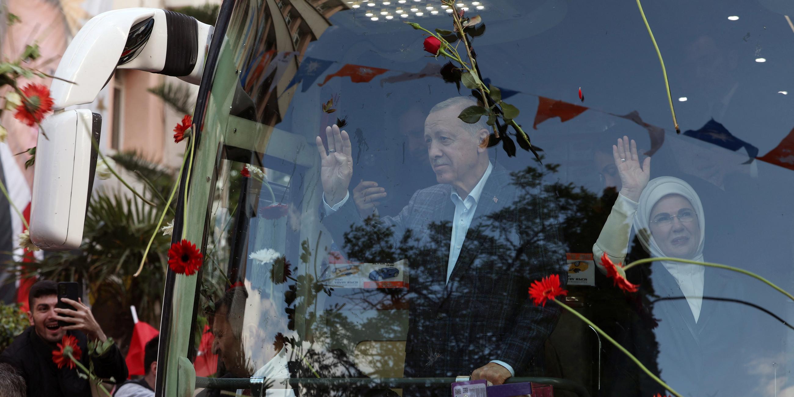 Der türkische Präsident Erdogan wird von seiner Frau Emine Erdogan begleitet und begrüßt seine Unterstützer als er in einem Bus auf einer Parade ankommt. Die Supporter werfen rote Blumen auf den Bus.