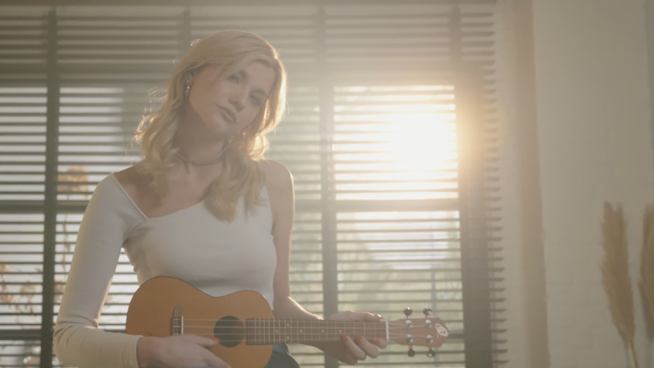 Die ehemalige "Dein Song"-Kandidatin Emily Fröhling steht vor einer großen Fensterfront und blickt in die Kamera. 