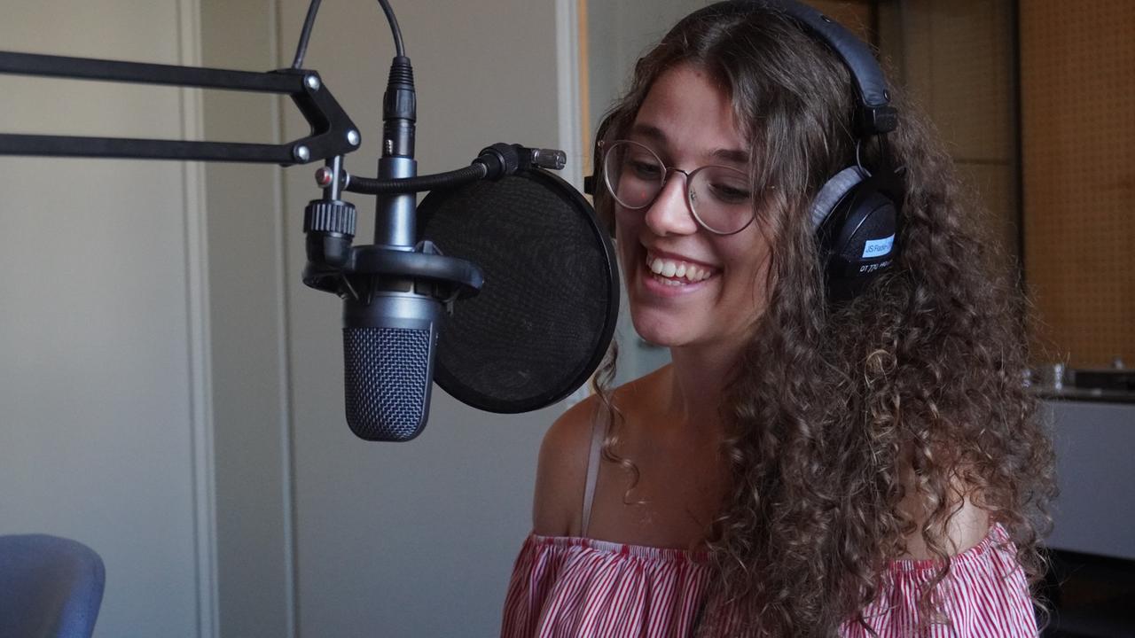 Die ehemalige "Dein Song"-Kandidatin Leontina sitzt lächelnd vor einem Mikrofon.