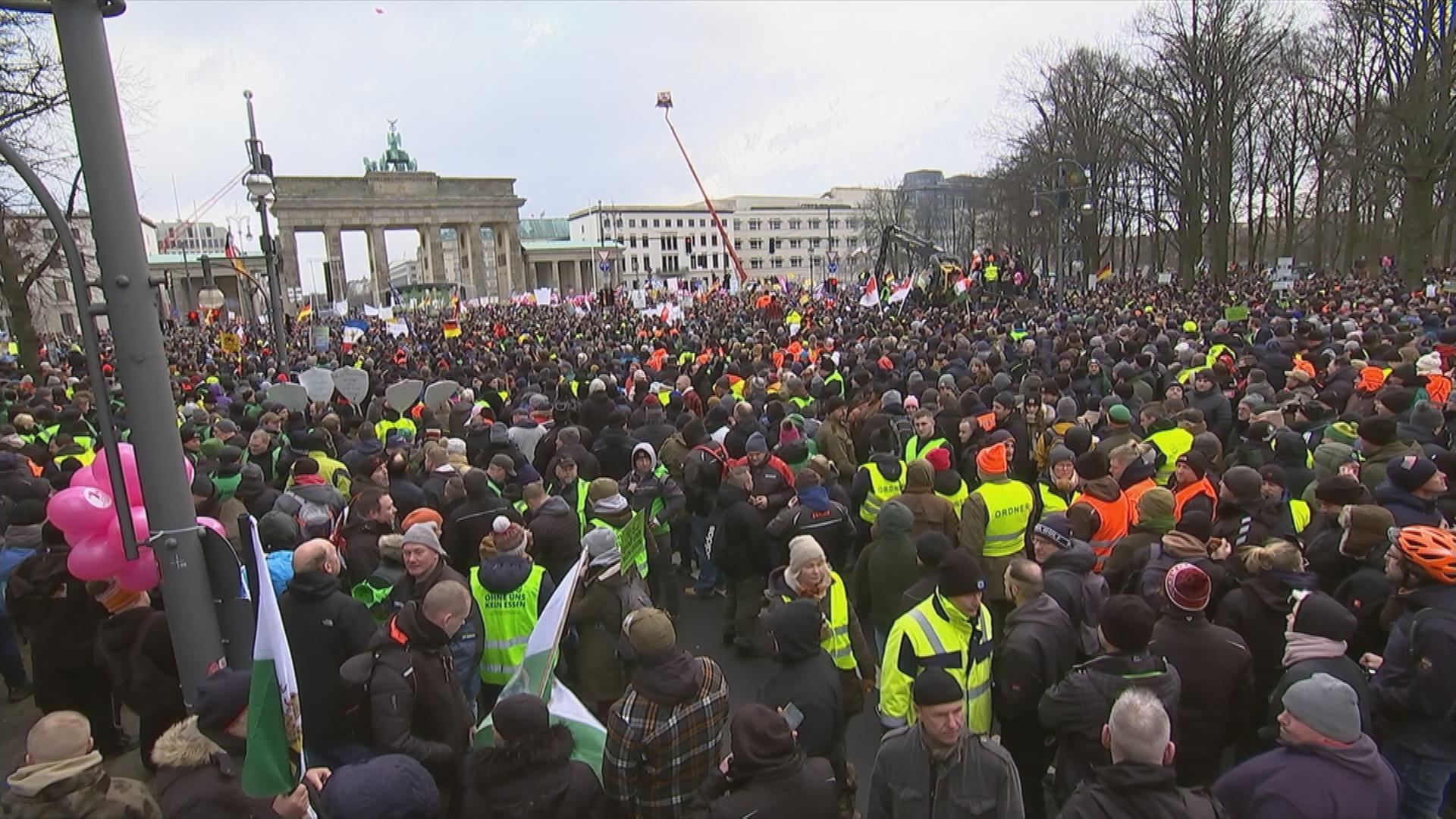 Auf dem Bild sieht man viele Menschen die vor dem Brandenburger Tor in Berlin stehen.