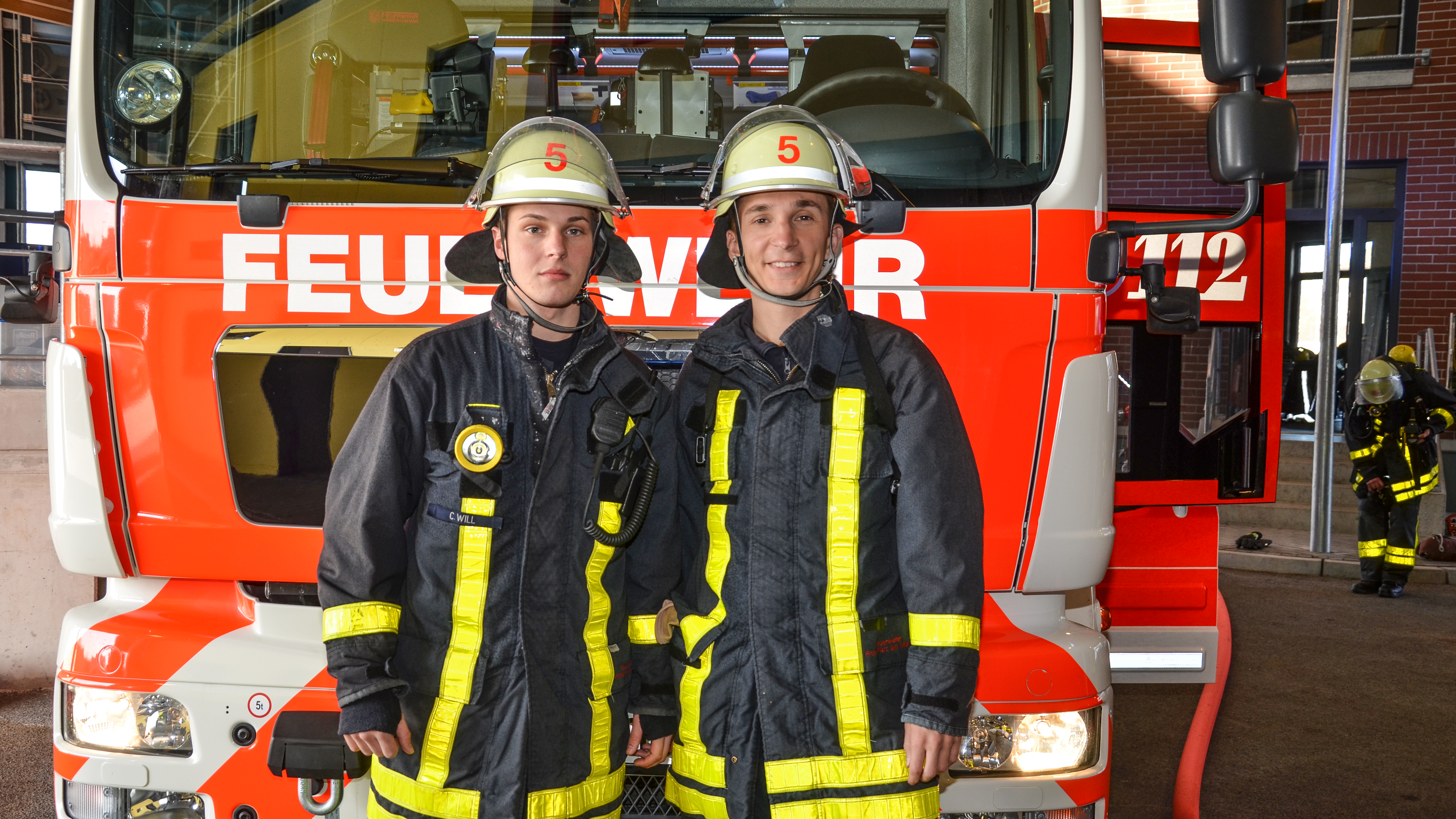 Eric in Feuerwehruniform vor einem Feuerwehrauto.
