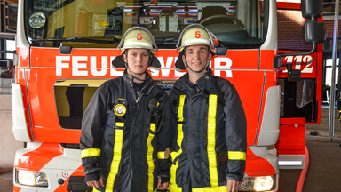 Eric in Feuerwehruniform vor einem Feuerwehrauto.