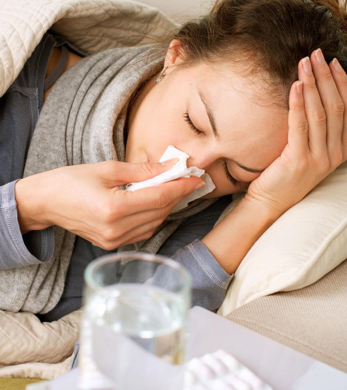 Frau liegt krank auf dem Sofa
