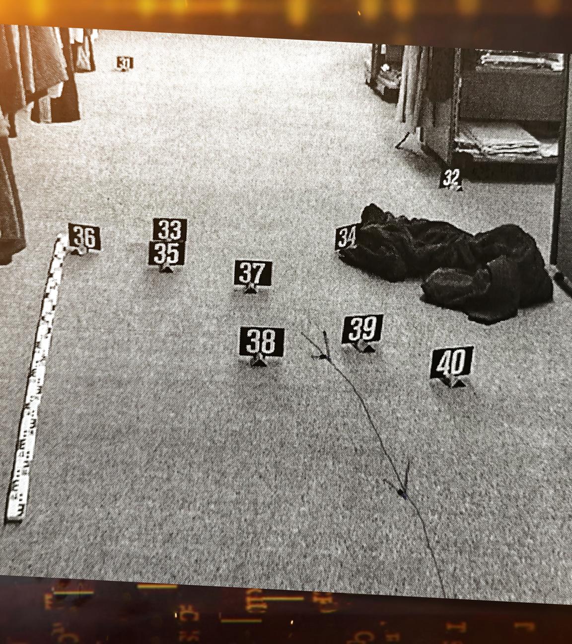 Der Tatort im Modegeschäft. Auf dem Boden sieht man den Bademantel, und einen Gürtel (Mordwaffe). Jegliche Spuren wurden mit Schildern markiert.