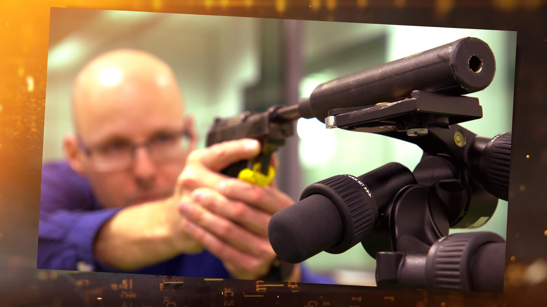 Ein Mann zielt mit einer Waffe zur Seite.