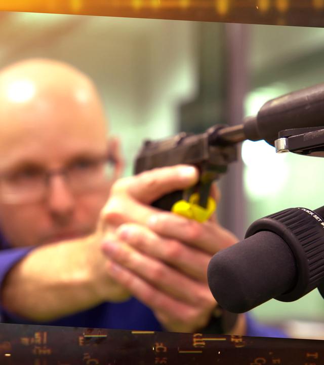 Ein Mann zielt mit einer Waffe zur Seite.