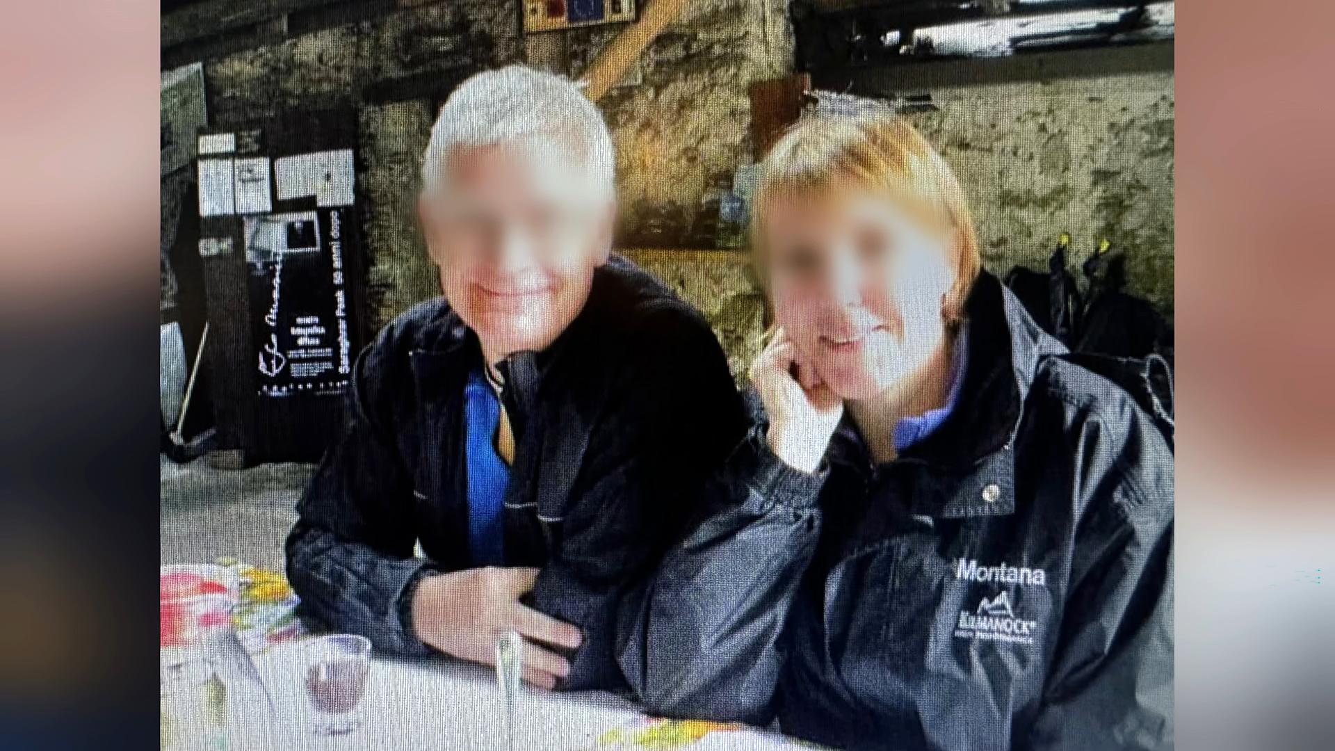 Bjarne und Heidi sitzen nebeneinander und blicken fröhlich in die Kamera. Beide tragen dunkle Anoraks. Ihre Gesichter wurden unkenntlich gemacht.