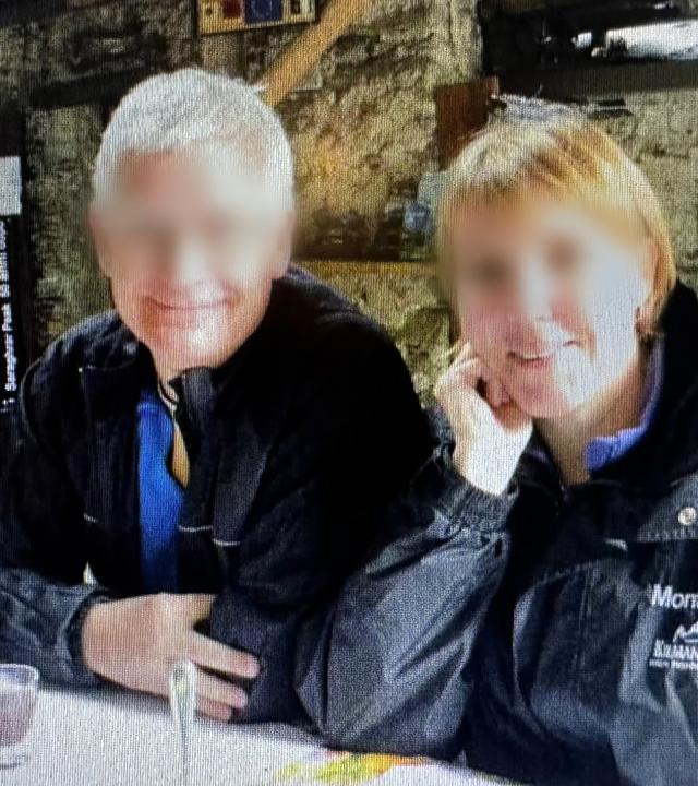 Bjarne und Heidi sitzen nebeneinander und blicken fröhlich in die Kamera. Beide tragen dunkle Anoraks. Ihre Gesichter wurden unkenntlich gemacht.