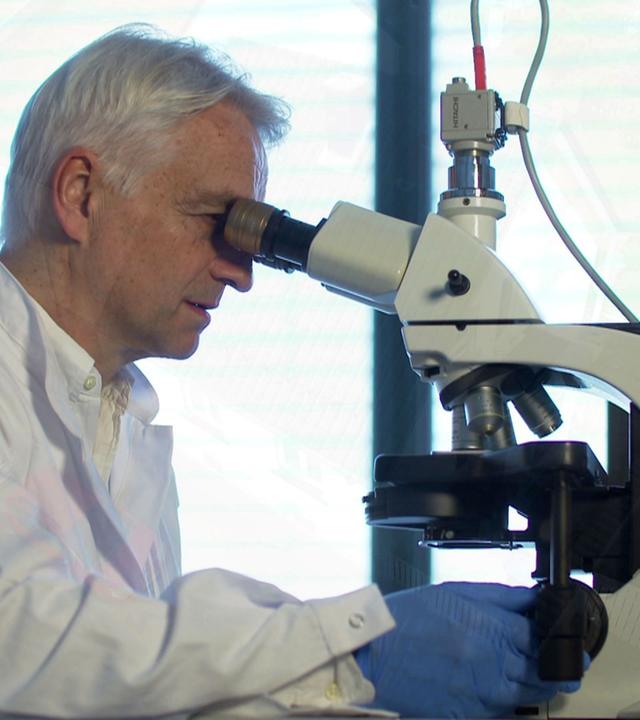 "Ermittler! - Gefährliche Einbrecher": Nahaufnahme von Dr. Harald Schneider beim Untersuchen am Mikroskop.