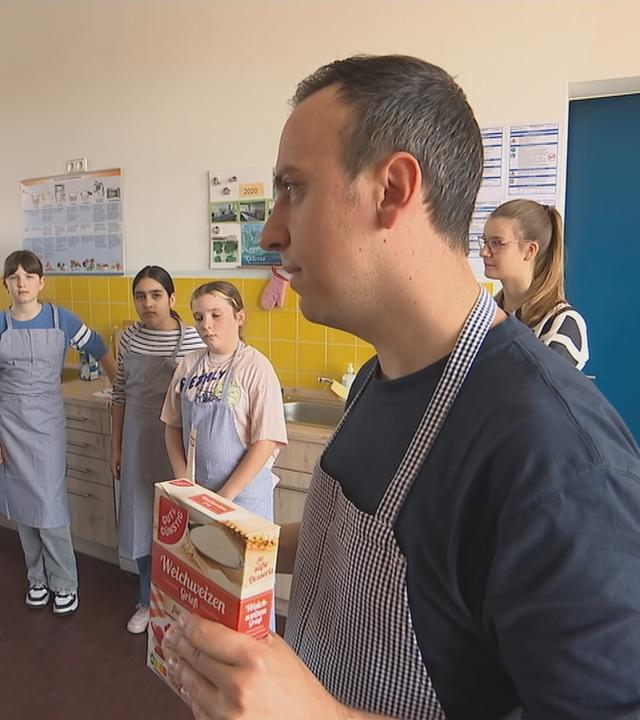 Lehrer steht mit Weizenmehl vor Kindern