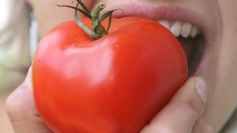  Frau beißt in Tomate