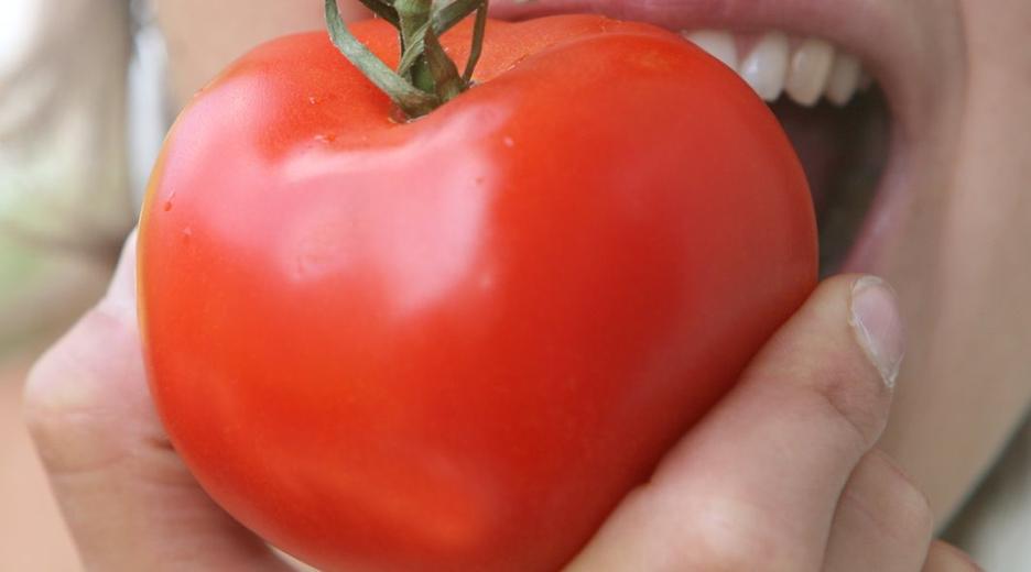  Frau beißt in Tomate
